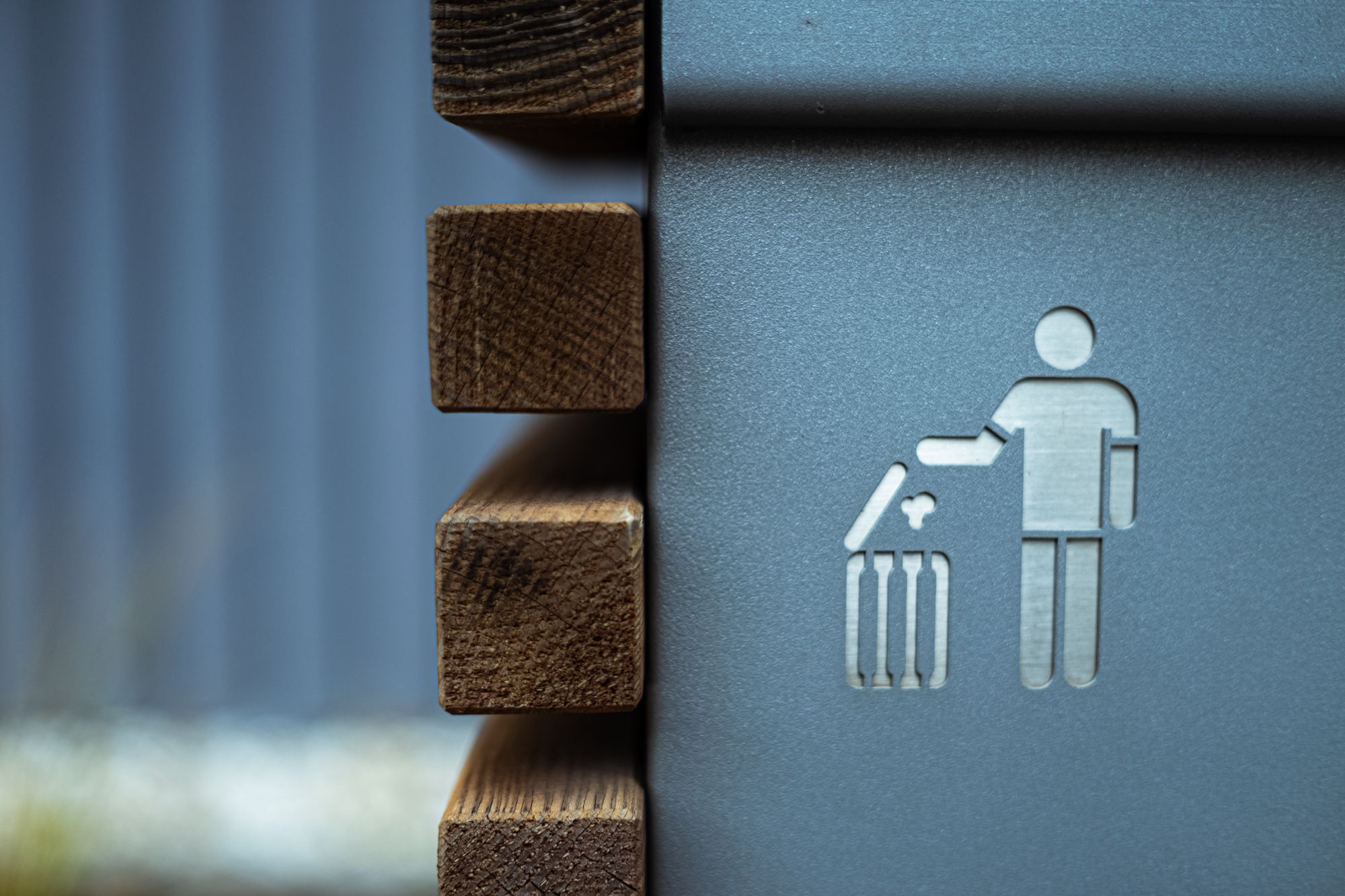 Sign on the side of a building with a human throwing away trash.