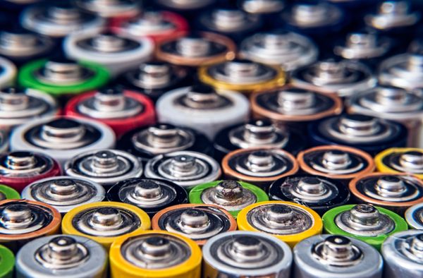 Large number of AA batteries standing upright.