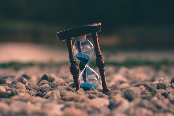 Sand clock sitting on a bed of pebbles.